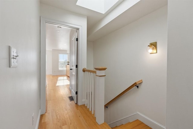 corridor featuring light hardwood / wood-style flooring and a skylight