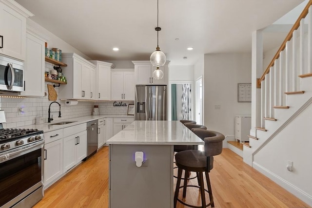 kitchen with sink, decorative light fixtures, a kitchen island, stainless steel appliances, and white cabinets