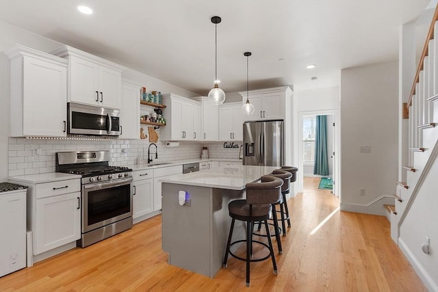 kitchen featuring white cabinetry, appliances with stainless steel finishes, a center island, and pendant lighting