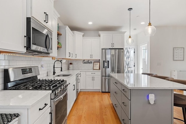 kitchen with white cabinetry, appliances with stainless steel finishes, a kitchen bar, and sink