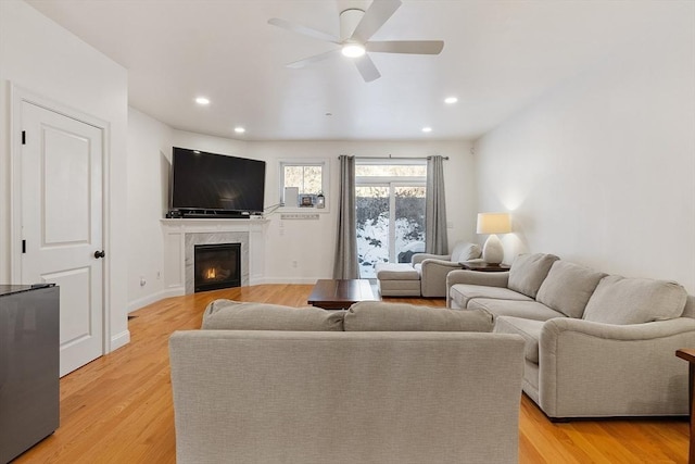 living room with ceiling fan, a fireplace, and light hardwood / wood-style flooring