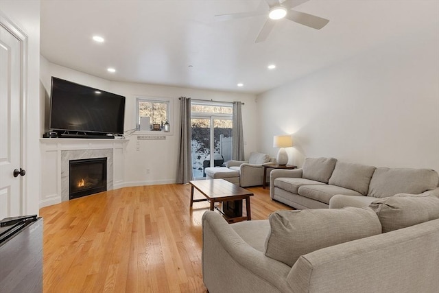 living room with wood-type flooring, a premium fireplace, and ceiling fan