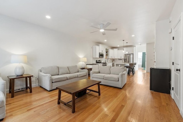 living room featuring ceiling fan and light hardwood / wood-style floors