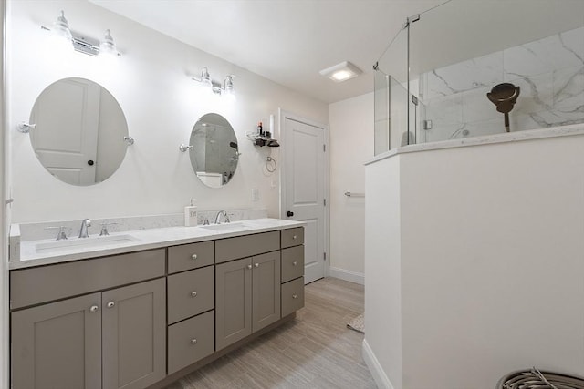 bathroom with hardwood / wood-style floors, vanity, and a tile shower