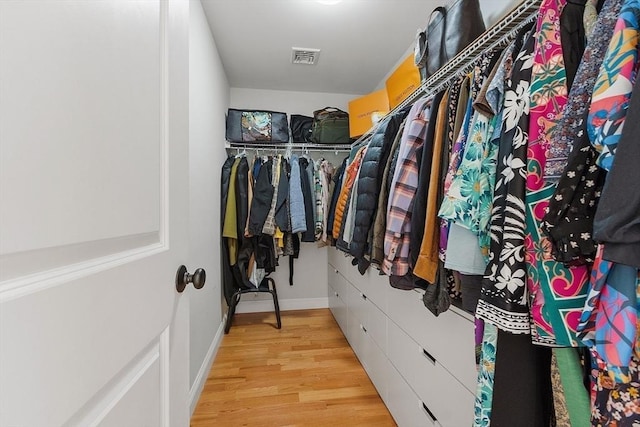 walk in closet with light hardwood / wood-style flooring