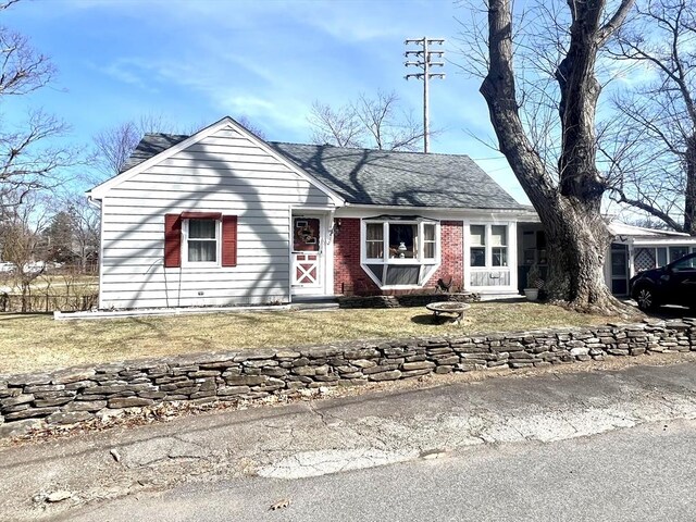 single story home featuring a front lawn, a shingled roof, and brick siding