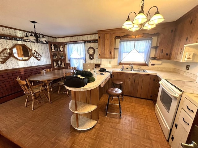 kitchen with a notable chandelier, light countertops, a sink, white electric stove, and wallpapered walls