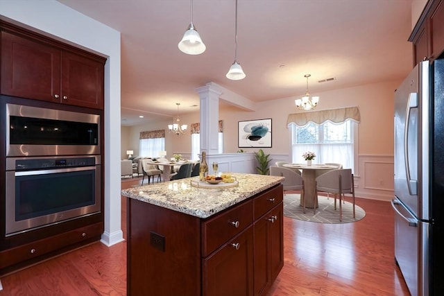 kitchen with a center island, an inviting chandelier, pendant lighting, and appliances with stainless steel finishes