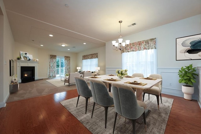 dining area with hardwood / wood-style floors and an inviting chandelier