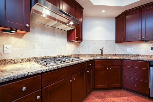 kitchen with light stone counters, ventilation hood, sink, light hardwood / wood-style floors, and stainless steel gas stovetop