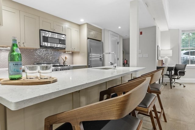 407 Shawmut Ave Unit 1, Boston, MA 02118 - kitchen featuring stainless steel appliances, light wood-style flooring, a breakfast bar, backsplash, and light stone countertops