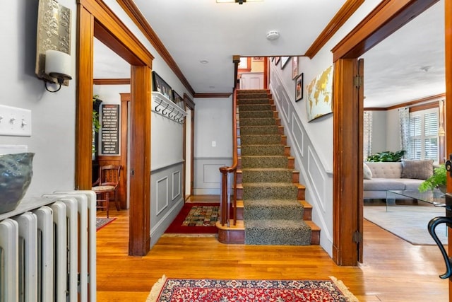 19 Beal Rd, Waltham, MA 02453 - staircase featuring radiator heating unit, ornamental molding, wood finished floors, a decorative wall, and wainscoting