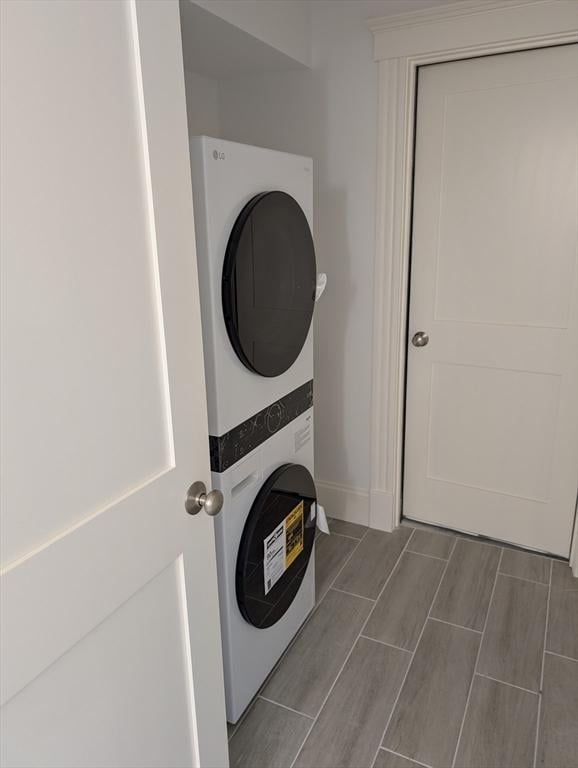 washroom with laundry area, baseboards, and stacked washer and dryer