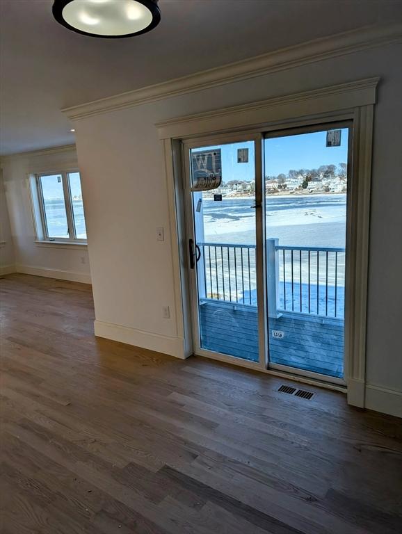 interior space featuring visible vents, baseboards, wood finished floors, and crown molding