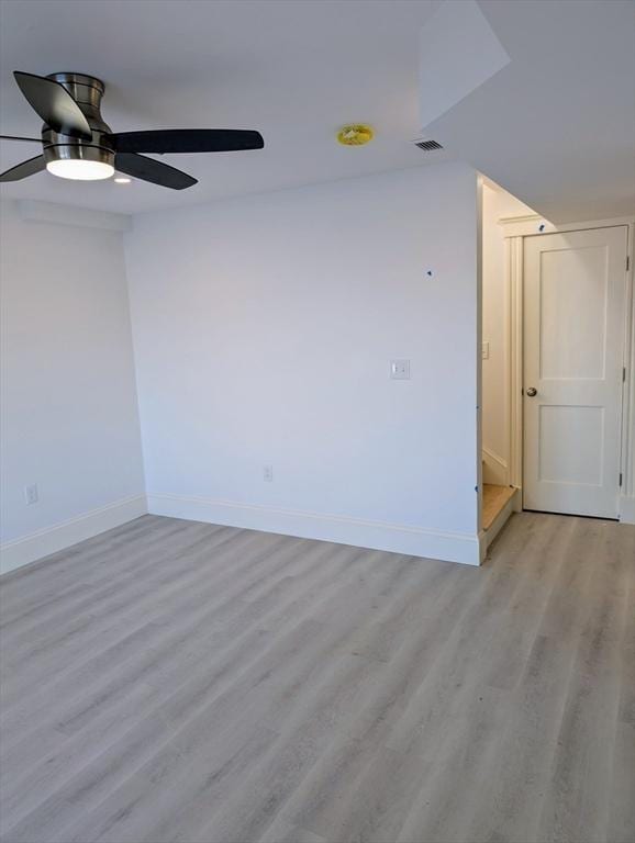 spare room featuring ceiling fan, light wood-style floors, visible vents, and baseboards