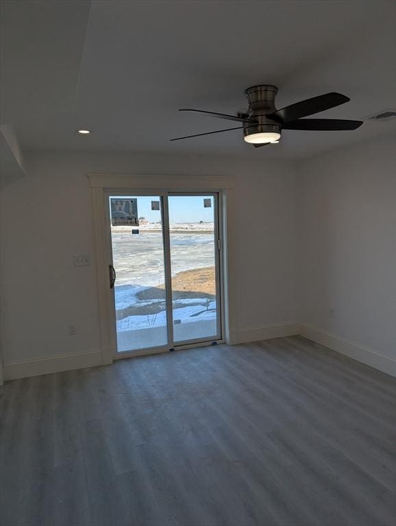 empty room featuring a ceiling fan, wood finished floors, visible vents, and baseboards