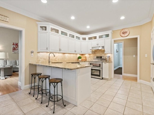 26 Silver Brook Ln Unit 26, Norwell, MA 02061 - kitchen featuring double oven range, a peninsula, light tile patterned flooring, decorative backsplash, and ornamental molding