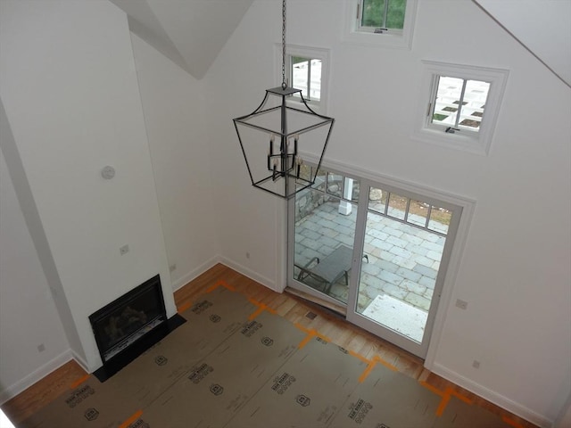 83 Johnson Woods Dr Unit 83, Reading, MA 01867 - unfurnished living room featuring wood finished floors, a chandelier, baseboards, a towering ceiling, and a fireplace with flush hearth