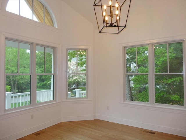 83 Johnson Woods Dr Unit 83, Reading, MA 01867 - empty room featuring light wood finished floors, a chandelier, baseboards, and high vaulted ceiling