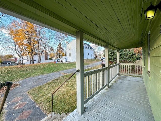 wooden terrace featuring covered porch and a yard