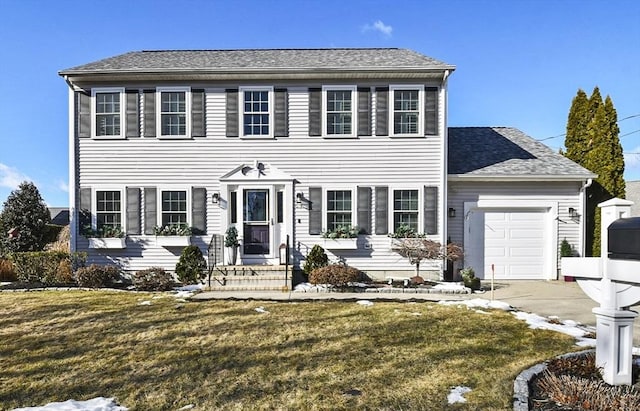 colonial-style house featuring a garage, driveway, a front lawn, and a shingled roof