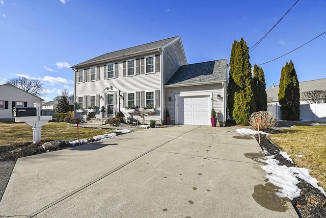 colonial house with a garage, concrete driveway, a front yard, and fence