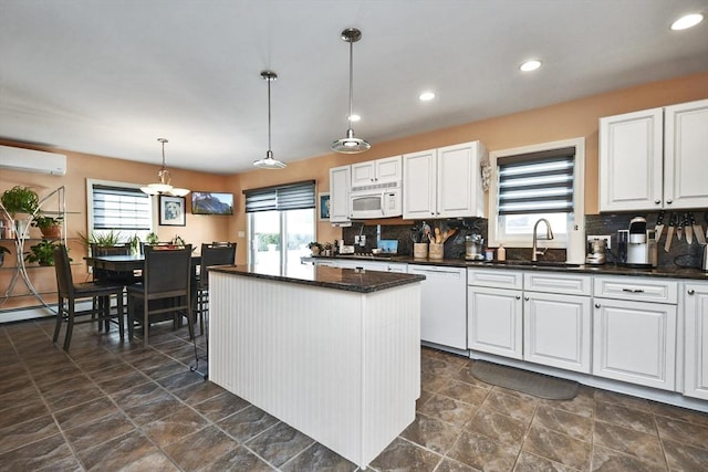 kitchen featuring pendant lighting, white appliances, white cabinets, and a sink