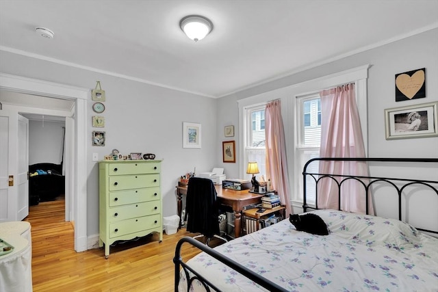 bedroom featuring light wood finished floors, ornamental molding, and attic access