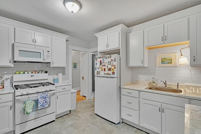 kitchen featuring white appliances, a sink, light countertops, and white cabinets