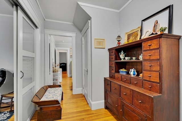 hallway featuring light wood-style floors, baseboards, and crown molding