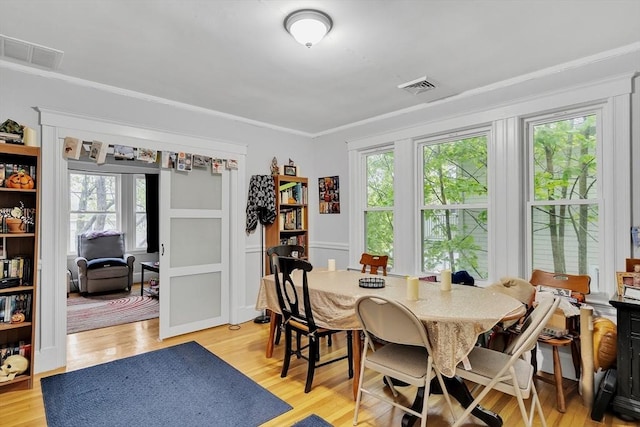 dining space with plenty of natural light, ornamental molding, and light wood-style flooring