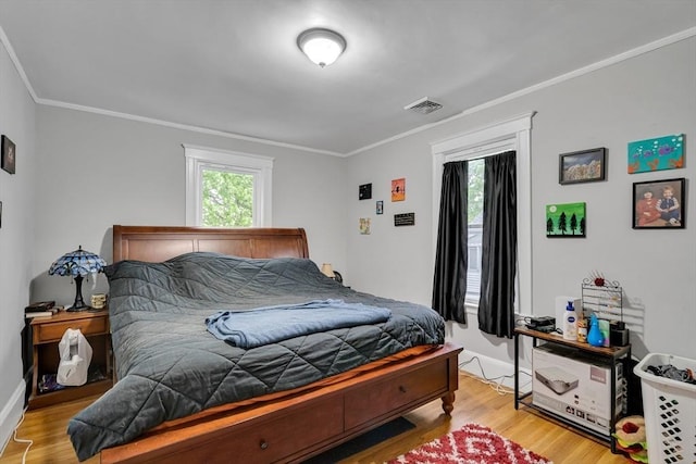 bedroom with wood finished floors, crown molding, and baseboards