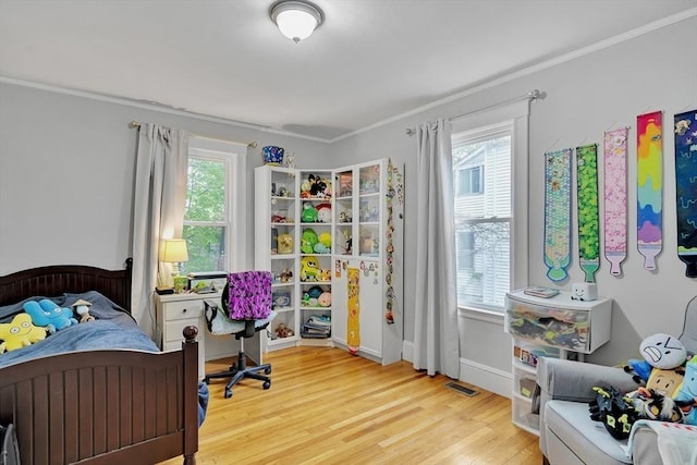 bedroom with multiple windows, light wood-style floors, and crown molding