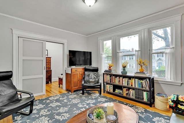 sitting room with light wood-style floors and crown molding