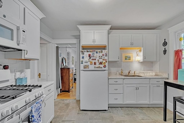 kitchen featuring white appliances, a sink, white cabinetry, and tasteful backsplash