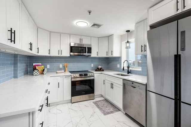 kitchen featuring white cabinets, appliances with stainless steel finishes, decorative light fixtures, decorative backsplash, and sink