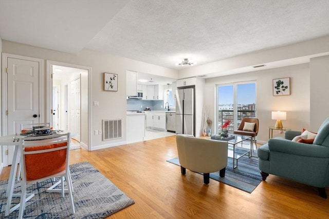 living room with sink and light hardwood / wood-style flooring