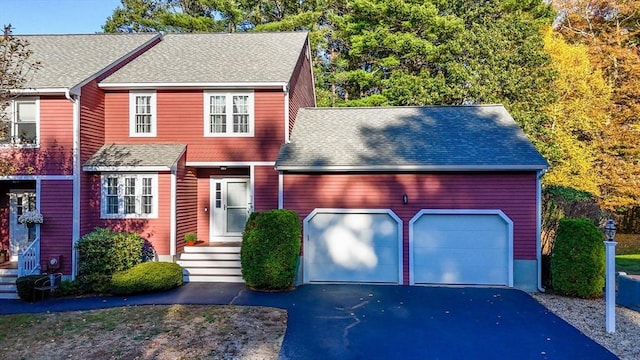 view of front of house featuring an attached garage, a shingled roof, and aphalt driveway