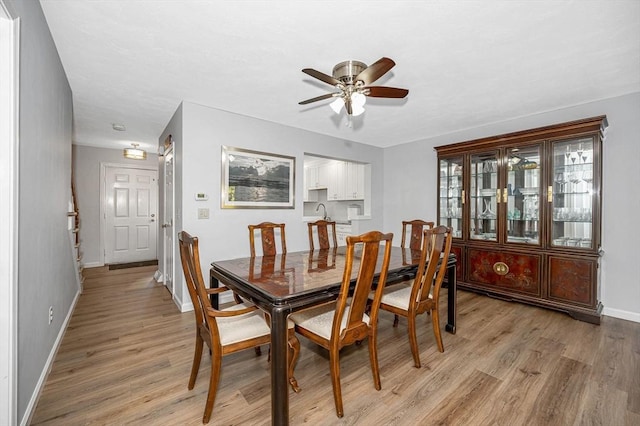 dining space with a ceiling fan, light wood-style flooring, and baseboards