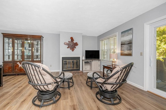 living area with baseboards, a fireplace, plenty of natural light, and light wood finished floors