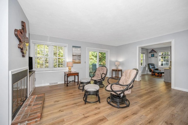 living area with baseboards, plenty of natural light, visible vents, and wood finished floors