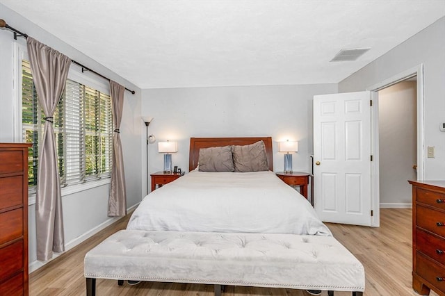 bedroom with baseboards, visible vents, and light wood-style floors