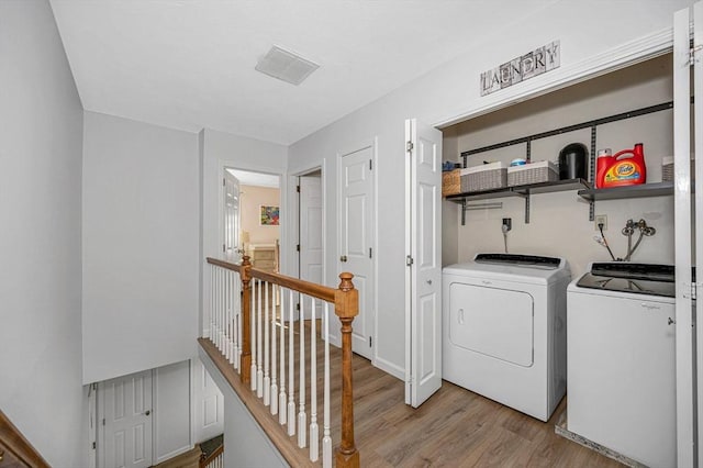 clothes washing area with laundry area, light wood finished floors, washer and clothes dryer, and visible vents