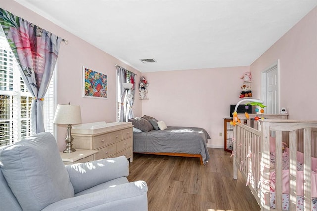 bedroom with baseboards, visible vents, and wood finished floors