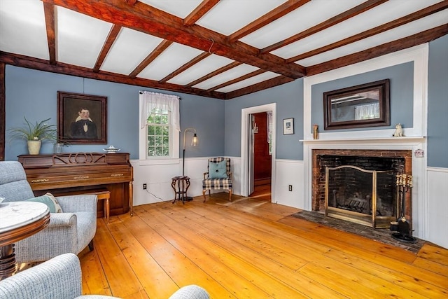 9 Eaton St, Gardner, MA 01440 - living area featuring light wood-style floors, a wainscoted wall, a fireplace with flush hearth, and beam ceiling