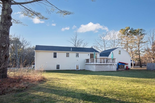 rear view of house featuring a wooden deck and a lawn