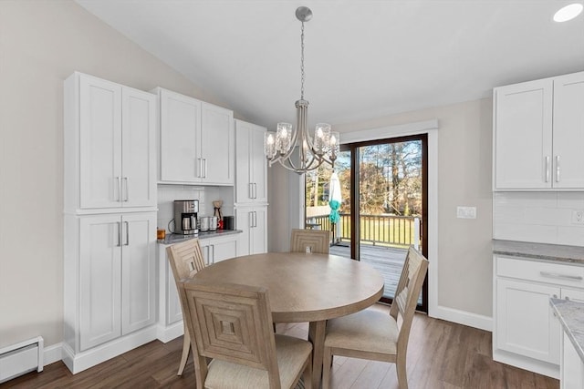 dining space with dark wood-type flooring, a chandelier, lofted ceiling, and a baseboard radiator