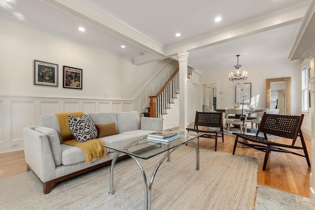 living room with light wood-type flooring, crown molding, and an inviting chandelier