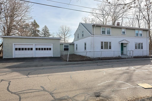 view of front of property featuring a chimney, a garage, and fence