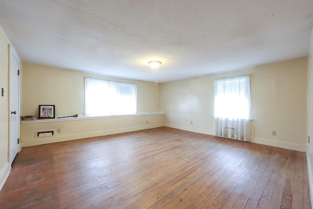 unfurnished room featuring a healthy amount of sunlight, baseboards, and hardwood / wood-style floors